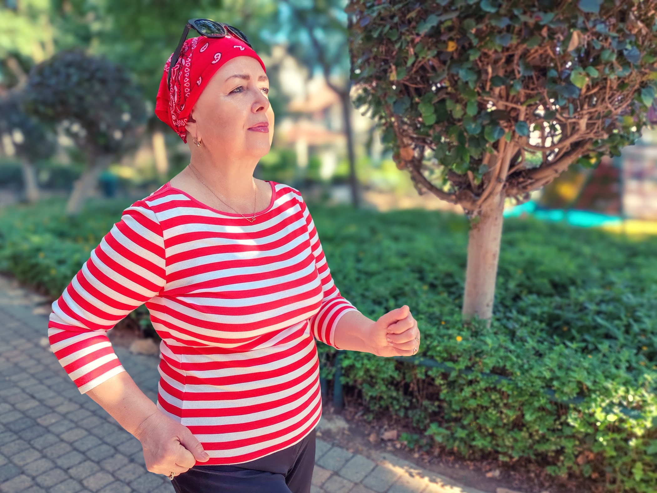 An empowered woman in a red-striped shirt is walking.