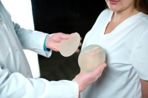 Plastic surgeon holds silicone breast implants.