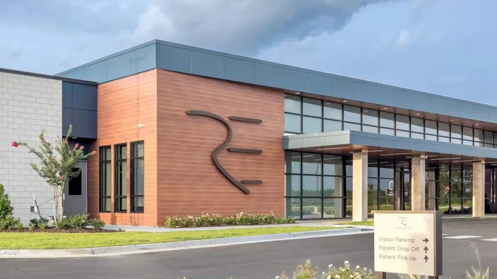ReCenter specialized breast cancer hospital exterior, a Contemporary building with wood and glass accents, a prominent "RE" logo, and a sign for ReCenter breast cancer hospital.