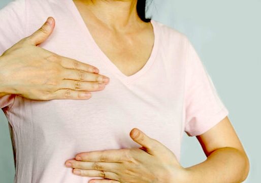 A closeup of a woman holding both hands over her breast.