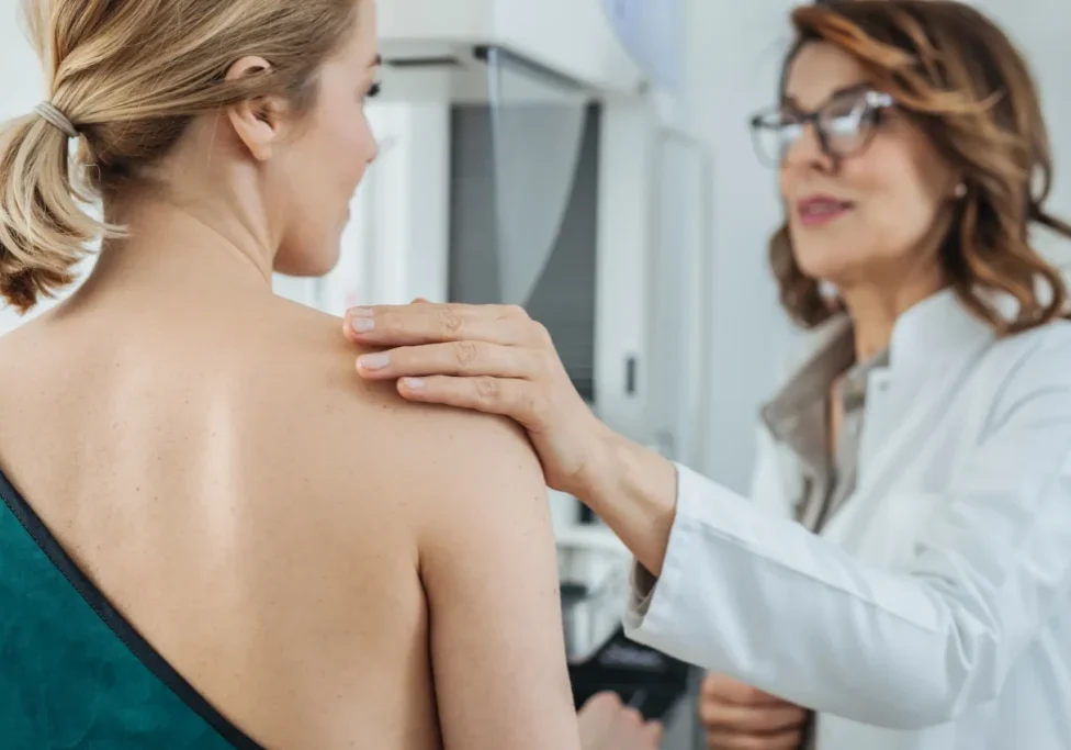 A healthcare professional supports a patient during a consultation about hybrid breast reconstruction surgery in a clinic.