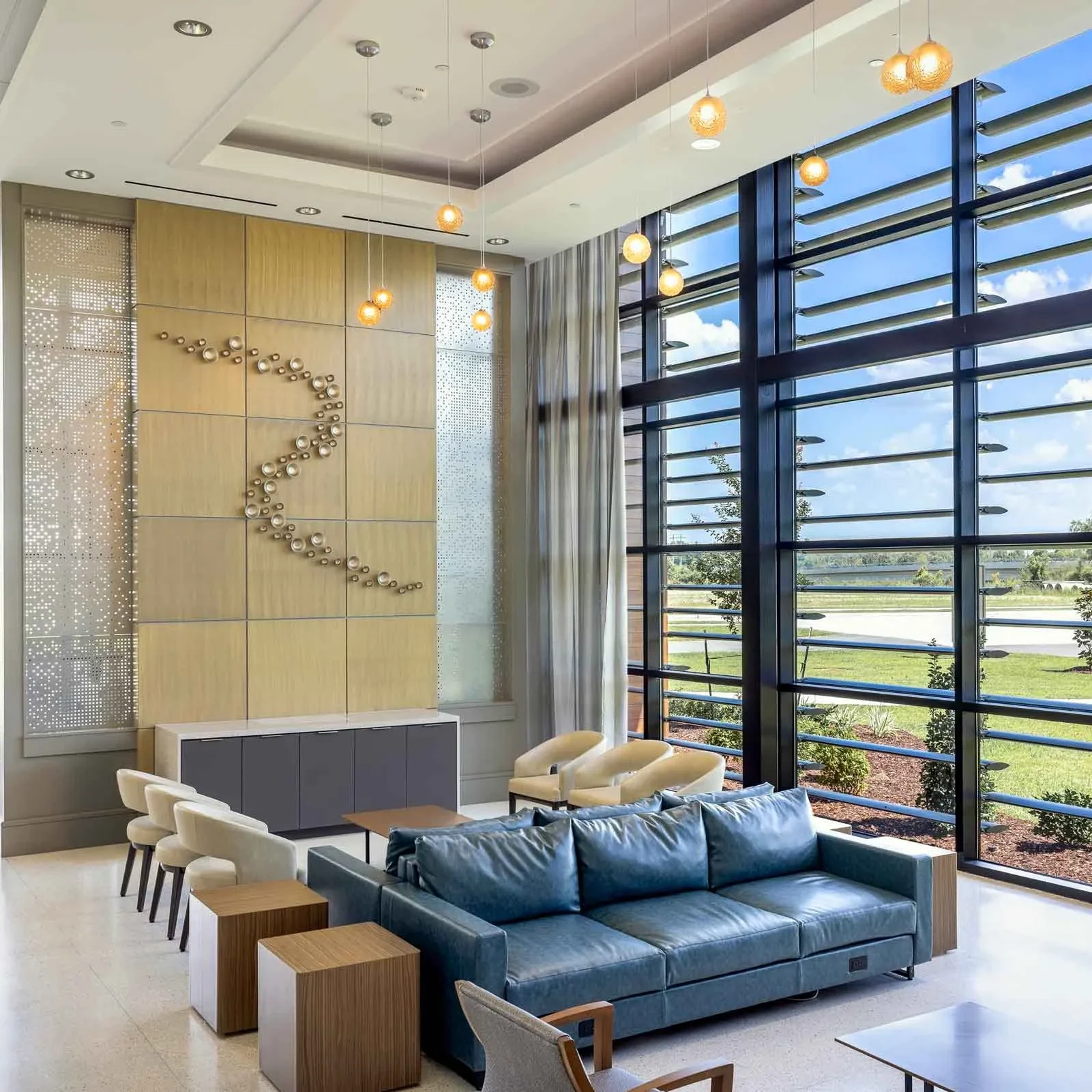 Modern ReCenter medical office lobby with floor-to-ceiling windows, contemporary seating, pendant lighting, and a decorative wall feature in a bright and welcoming healthcare environment.