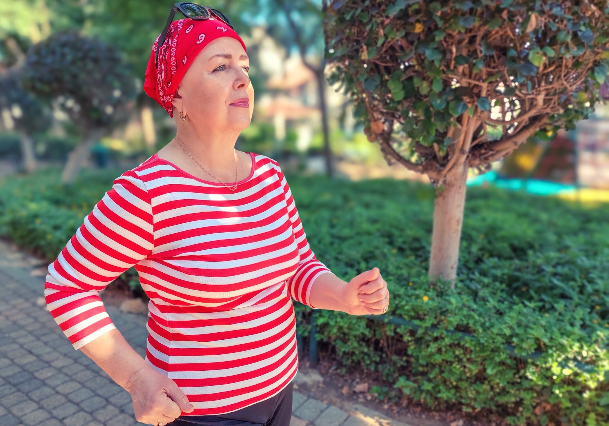 An empowered woman in a red-striped shirt is walking.