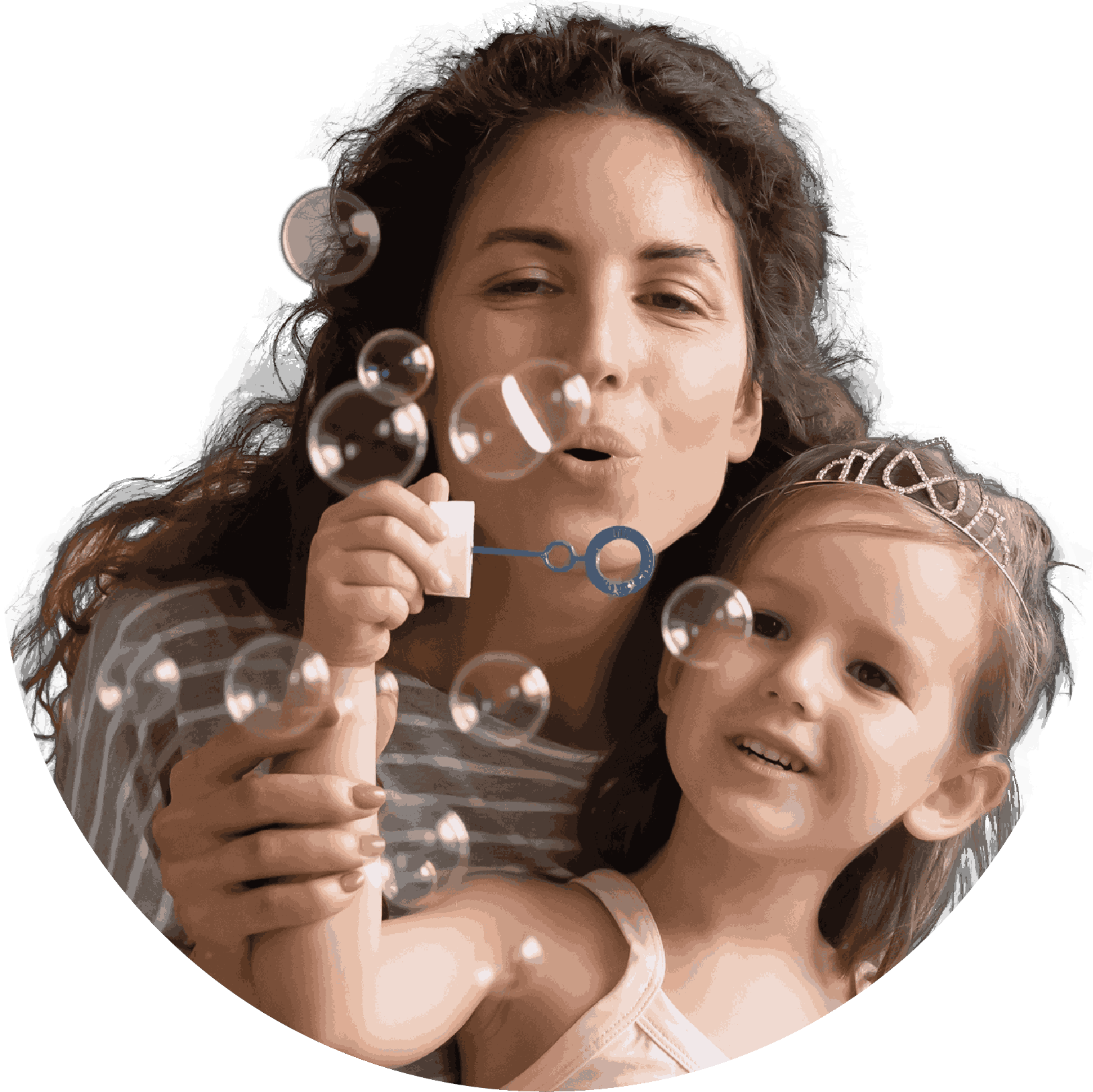 A smiling woman and young girl blow bubbles together while sharing a joyful moment.